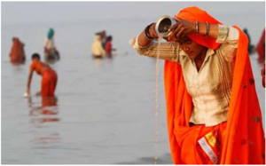 A woman doing teerthayatra at a river.png